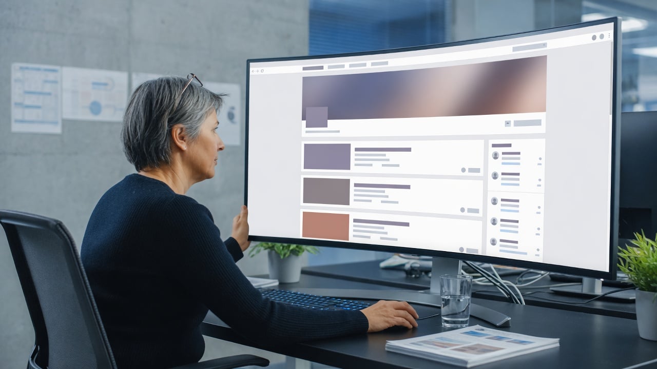 Administrator reviewing a magazine-style forum homepage on a widescreen monitor