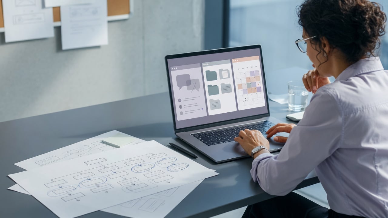 Community administrator at a slate desk reviewing a multi-section community site with discussion, files, and calendar panels